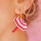 Mujer con pendientes de metacrilato con forma de sombrilla de playa a rayas rojas