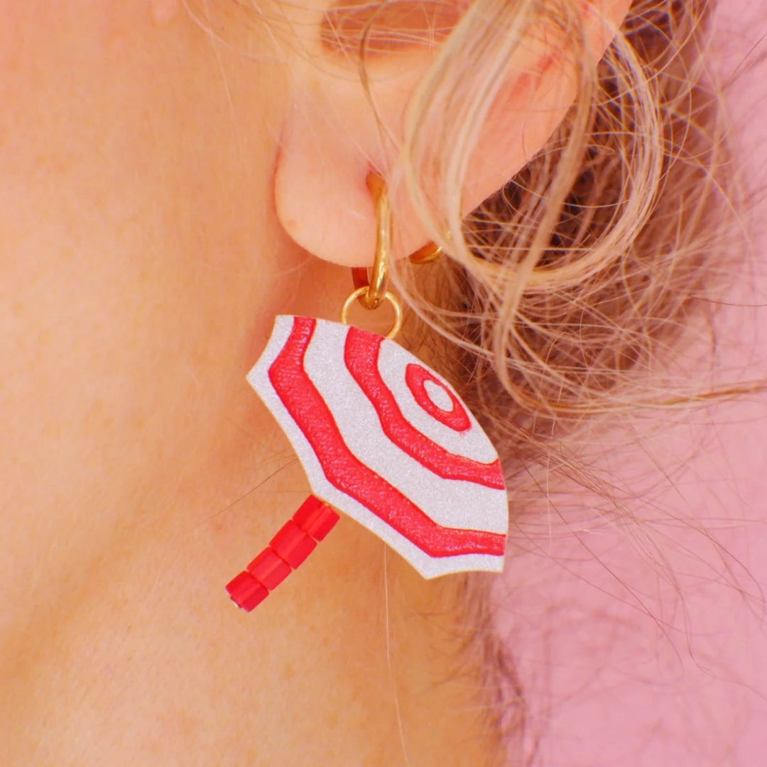 Mujer con pendientes de metacrilato con forma de sombrilla de playa a rayas rojas