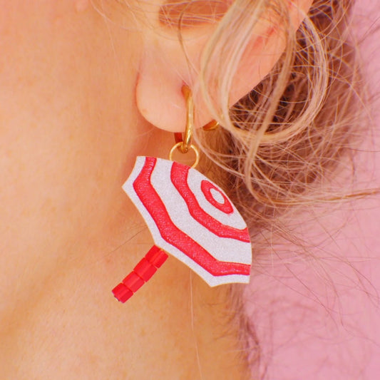 Mujer con pendientes de metacrilato con forma de sombrilla de playa a rayas rojas