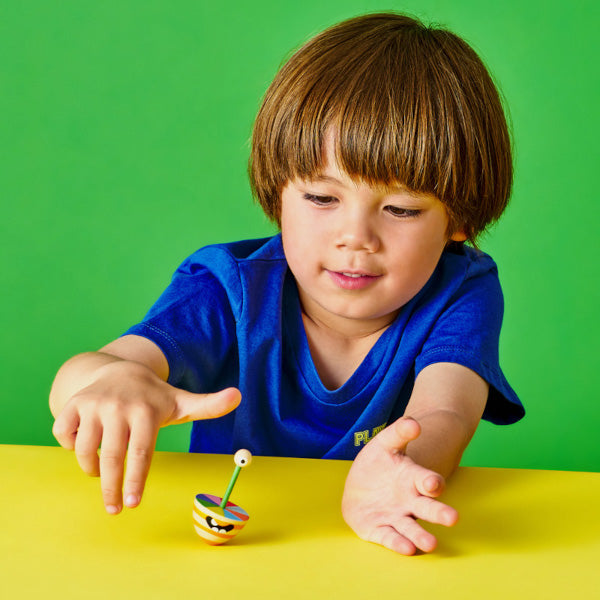 Niño jugando con una mini peonza de madera con forma de monstruo