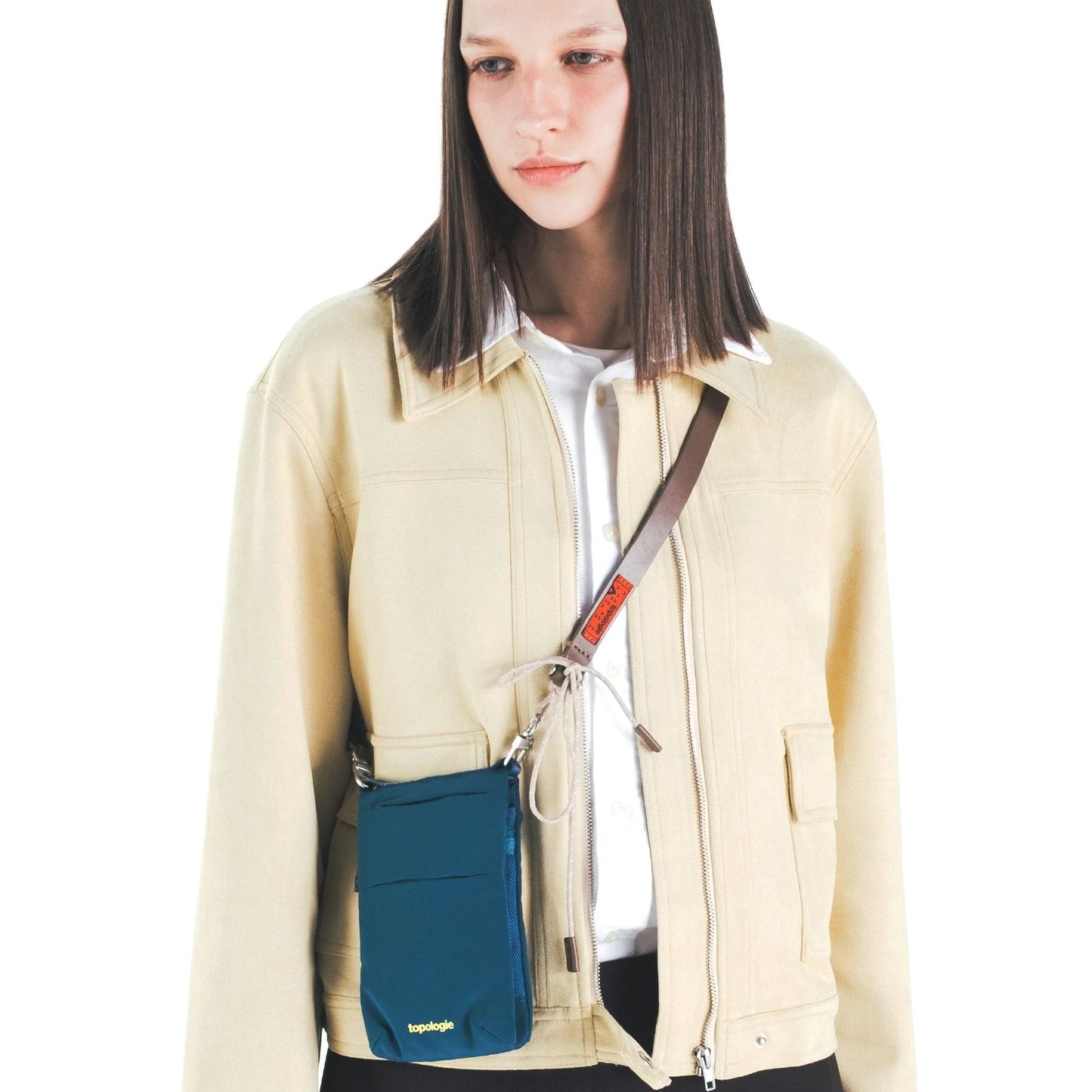 Mujer con el bolso Phone Sacoche de Topologie en color Turquesa satén colgado en bandolera con una correa de la misma marca