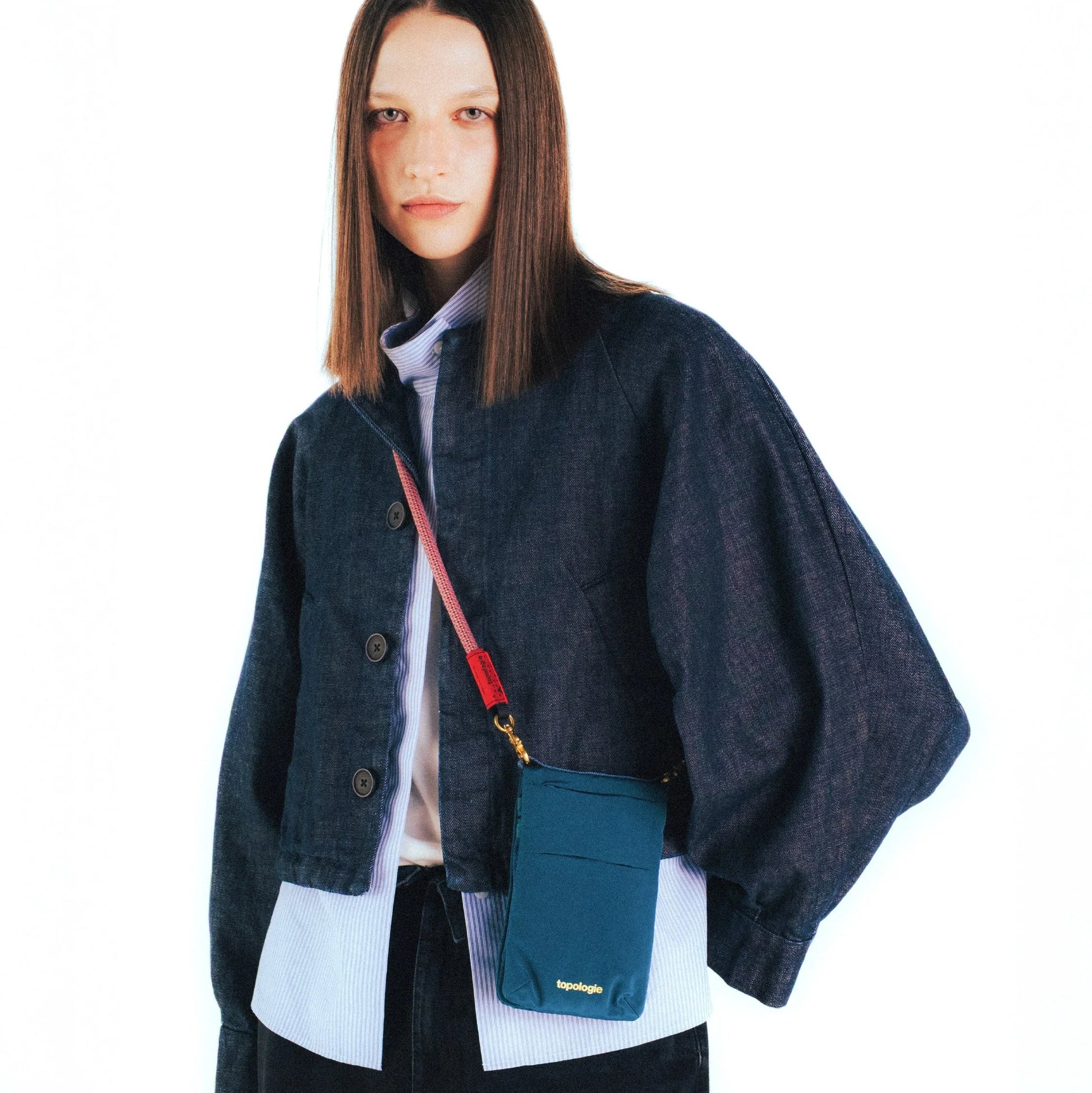 Mujer con el bolso Phone Sacoche de Topologie en color Turquesa satén colgado en bandolera