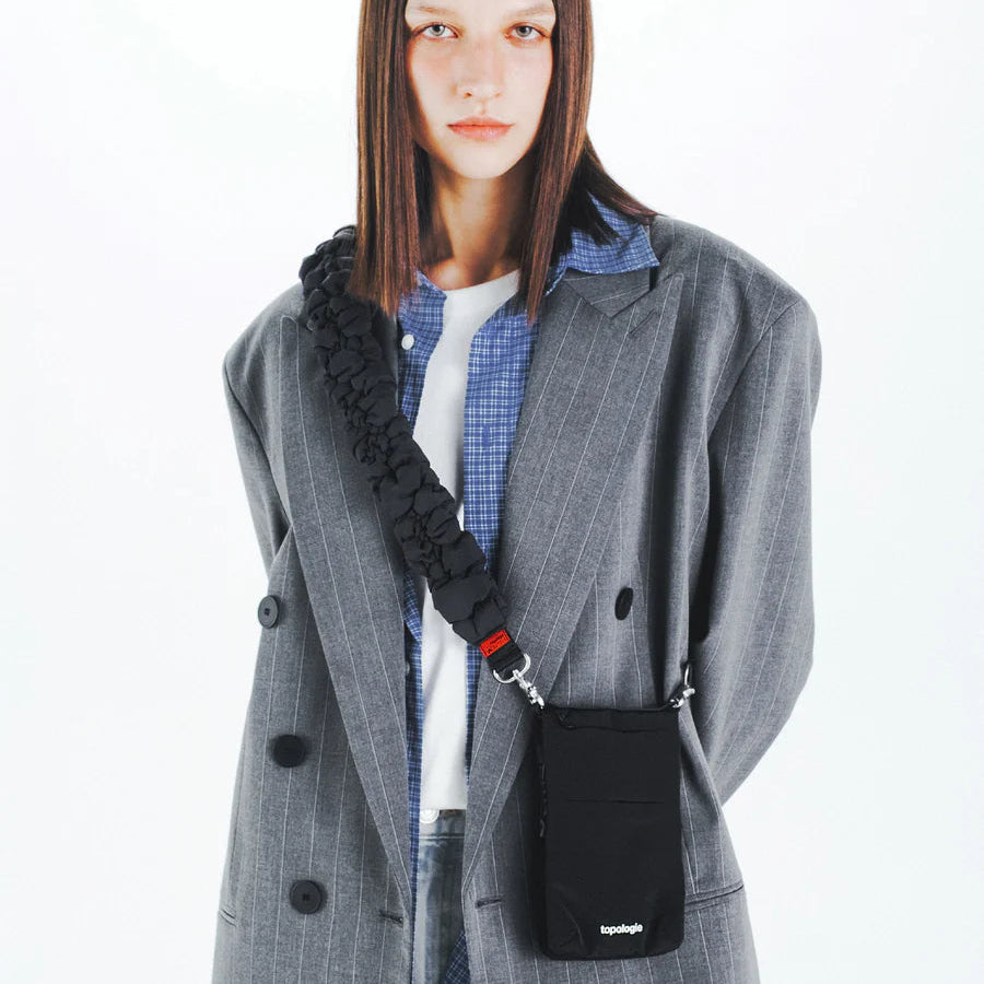 Mujer con el bolso Phone Sacoche negro satén de Topologie colgado en bandolera con una correa de la marca