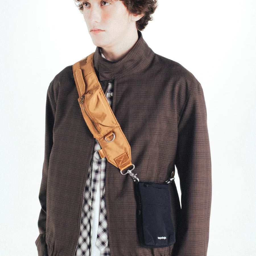 Hombre con el bolso Phone Sacoche negro satén de Topologie colgado en bandolera con una correa de la marca