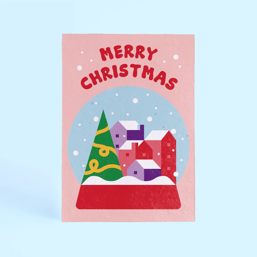 Tarjeta de Navidad plantable de Resetea, con ilustración de un pueblecito nevado dentro de una bola de nieve y el mensaje Merry Christmas