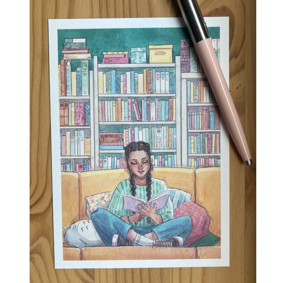 Postal con ilustración de Esther Gili de una chica en un sofá leyendo un libro