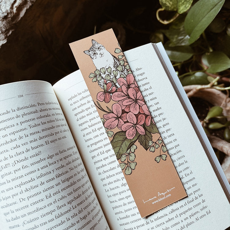 Libro abierto con marcapáginas ilustrado por Laura Agustí con un gato siamés y flores 