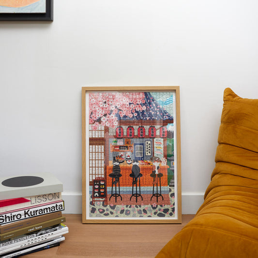 Puzzle de 1000 piezas con ilustración de tres gatos comiendo sushi en un restaurante japonés enmarcado