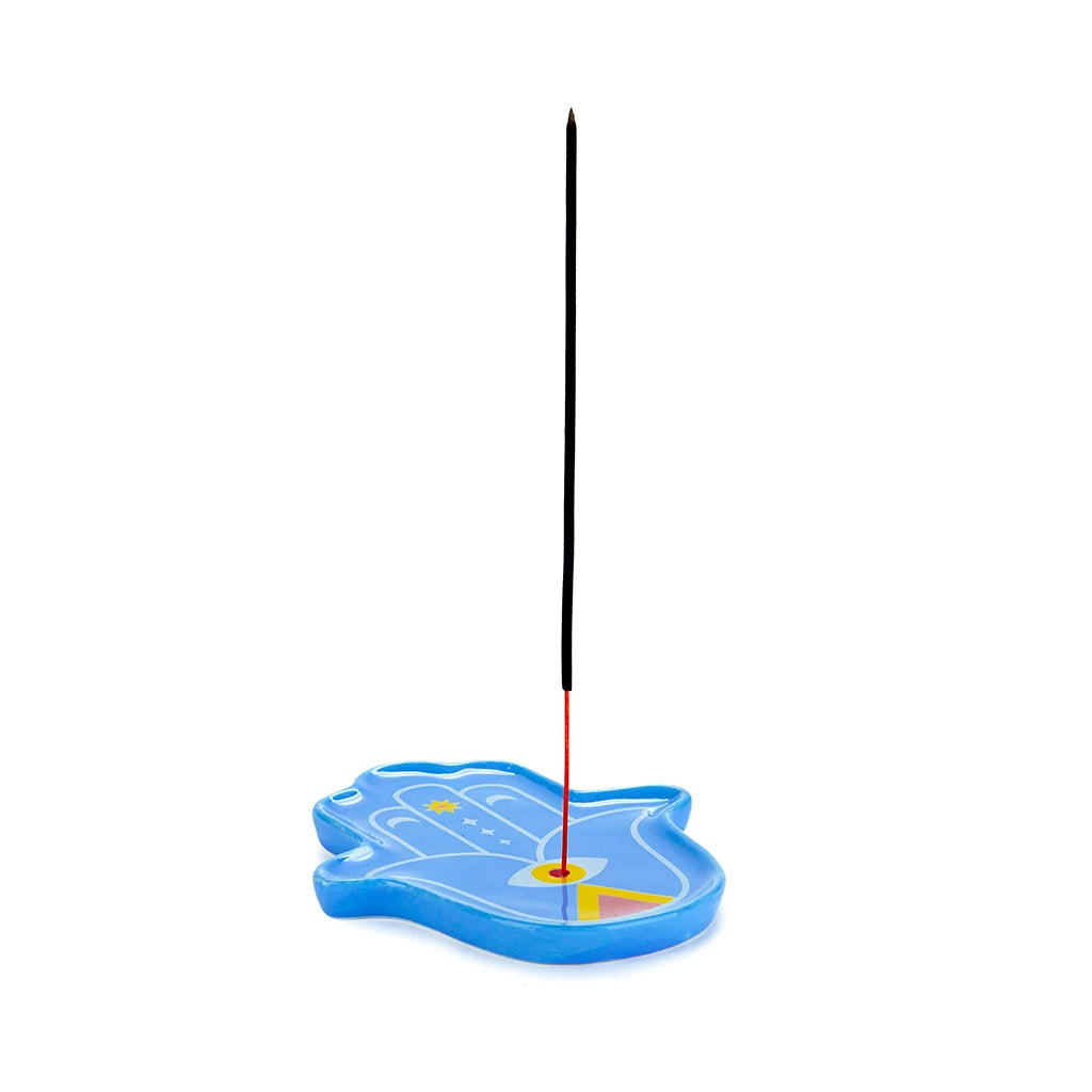 Quemador de incienso azul de cerámica con forma de mano de Fátima o Hamsa con una varilla de incienso pinchada