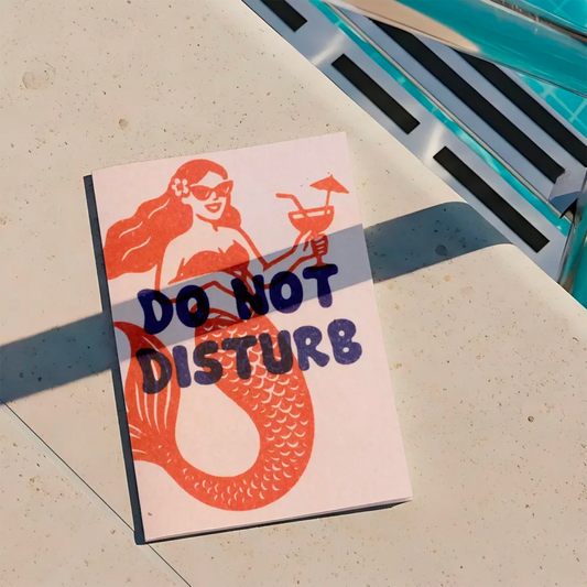 postal con semillas dentro de la marca resetea con una sirena sonriendo con gafas de sol y una bebida en la mano dibujada en color rojo con el texto Do Not Disturb en color azul