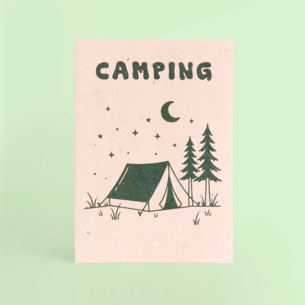 postal con semillas dentro de la marca resetea con un dibujo de una tienda de campaña, unos árboles y la luna y las estrellas con el texto Camping