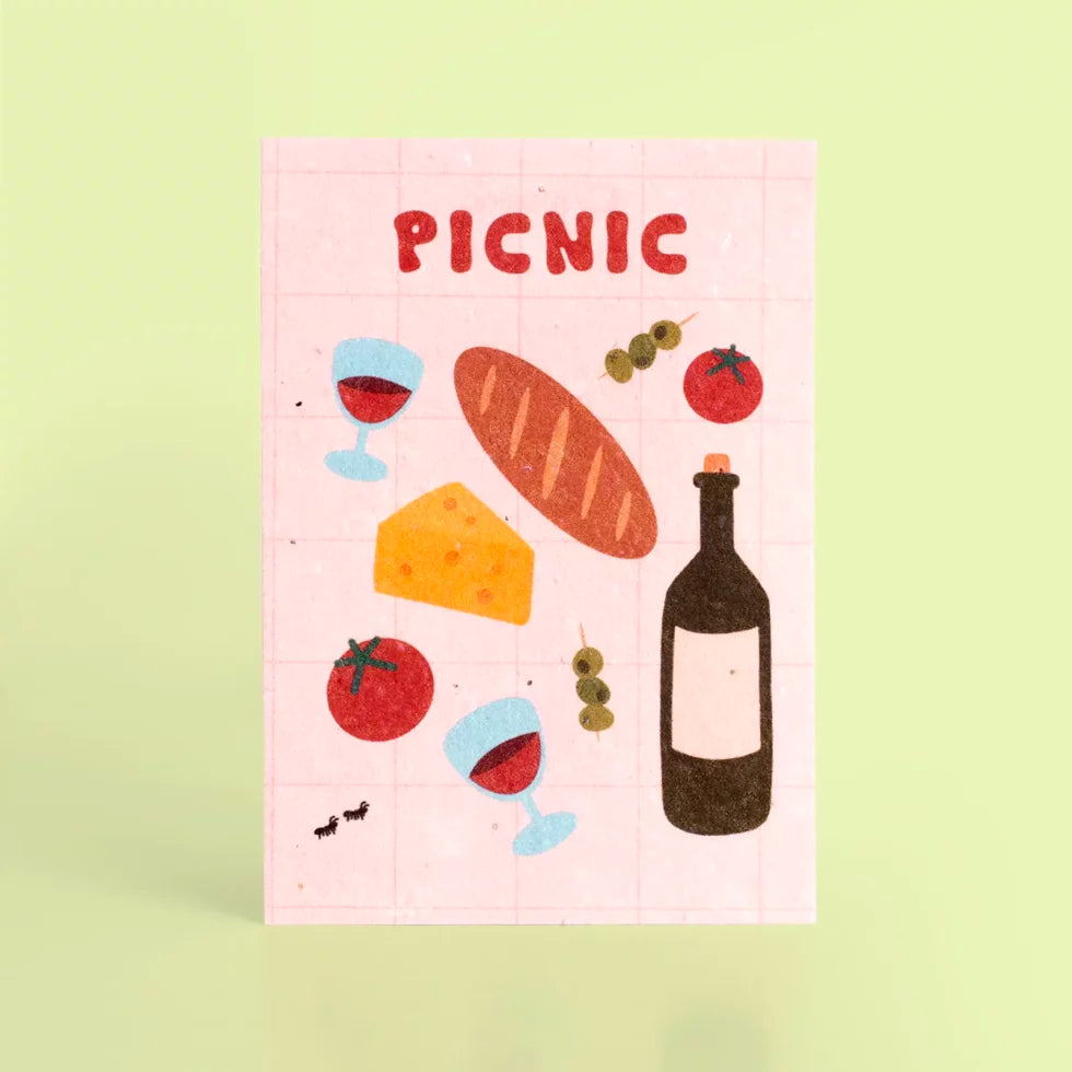 postal con semillas dentro de la marca resetea con dibujos de una barra de pan, dos gildas tomate, queso, copas de vino y una botella de vino y el texto PICNIC