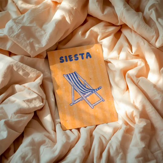 postal con semillas dentro de la marca resetea con el fondo a rayas amarillas, una tumbona a rayas dibujada en azul y el texto SIESTA también en azul