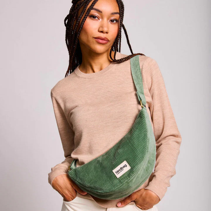Mujer con bolso riñonera en forma de media luna con tejido de pana verde agua