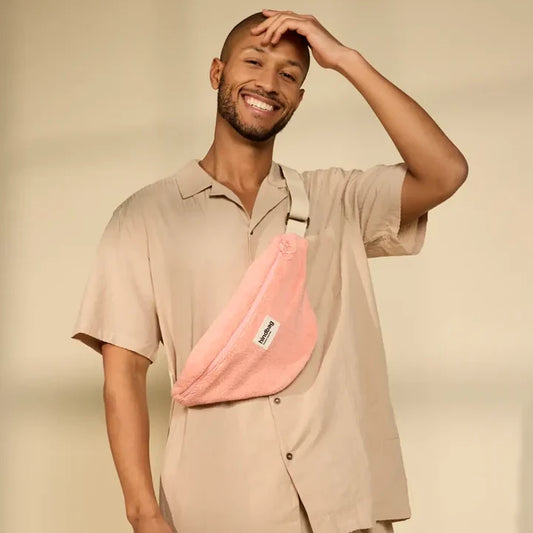 Hombre vestido de beige con una riñonera de rizo rosa de la marca francesa Hindbag