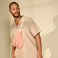 Hombre vestido de beige con una riñonera de rizo rosa de la marca francesa Hindbag