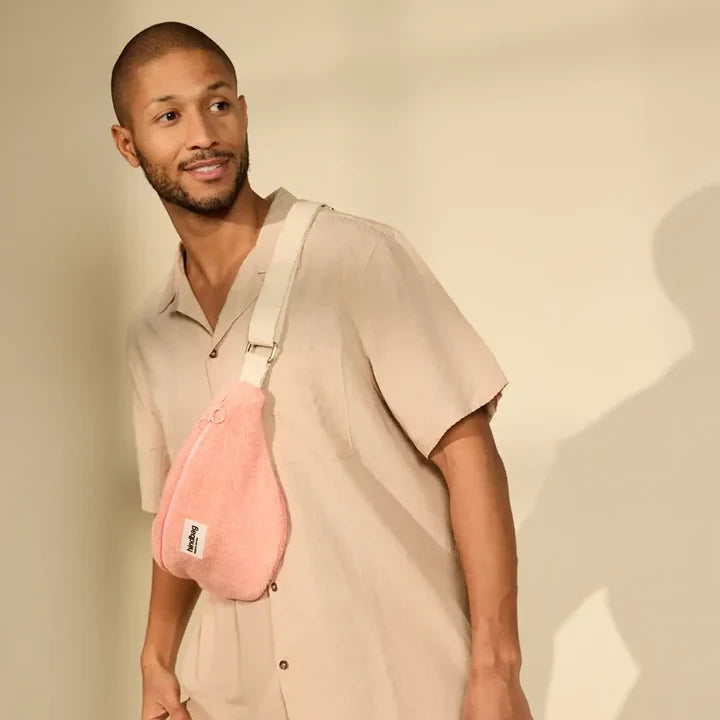 Hombre vestido de beige con una riñonera de rizo rosa de la marca francesa Hindbag