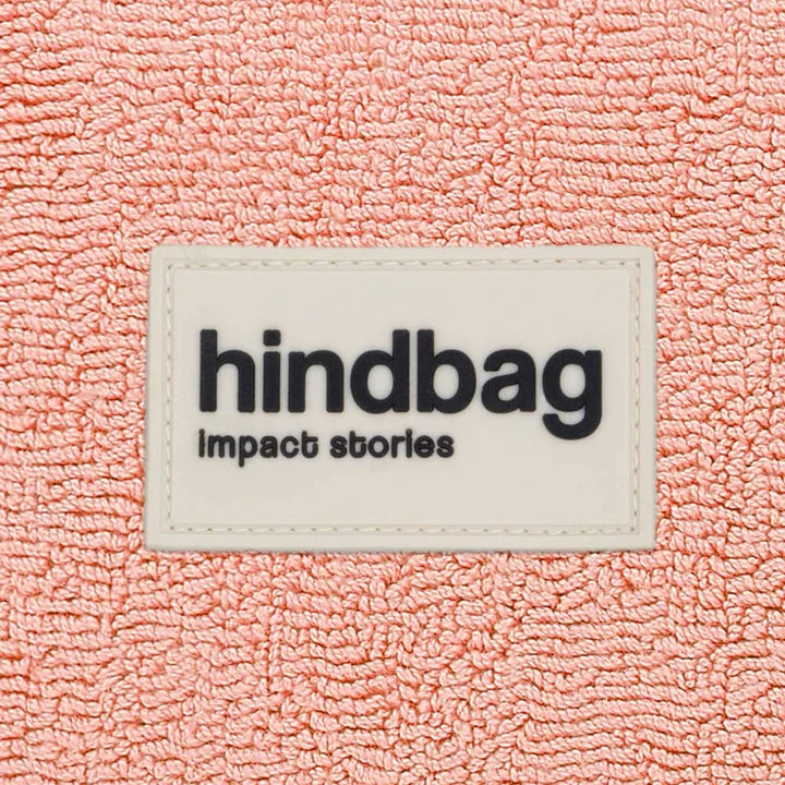 Detalle del tejido y la etiqueta frontal de la riñonera de rizo rosa de la marca francesa Hindbag