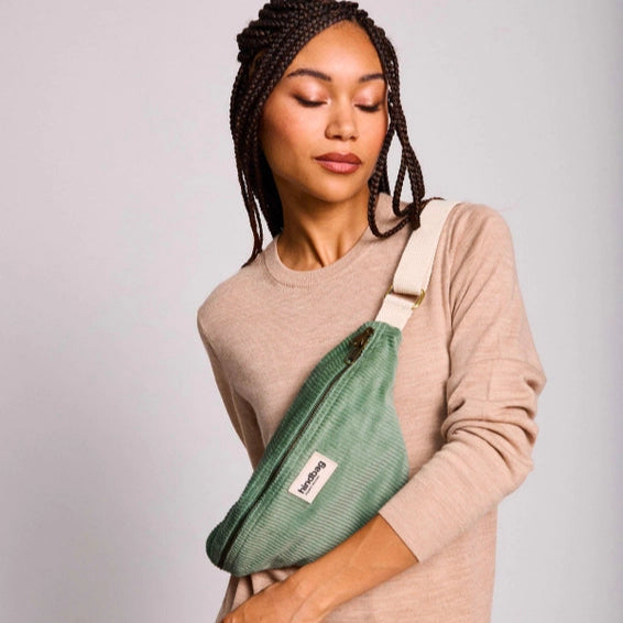 Mujer con trenzas y una riñonera de pana modelo Olivia de Hindbag color verde agua