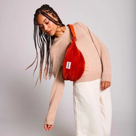 Chica con una riñonera de pana de color rojo ladrillo de la marca francesa Hindbag