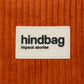 Detalle del tejido y la etiqueta de la marca Hindbag del bolso de pana de color rojo ladrillo 