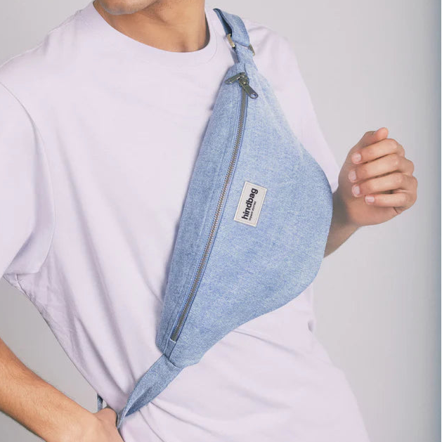 Riñonera de la marca Hindbag en vaquero clarito puesta en el torso de una persona.