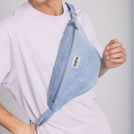 Riñonera de la marca Hindbag en vaquero clarito puesta en el torso de una persona.
