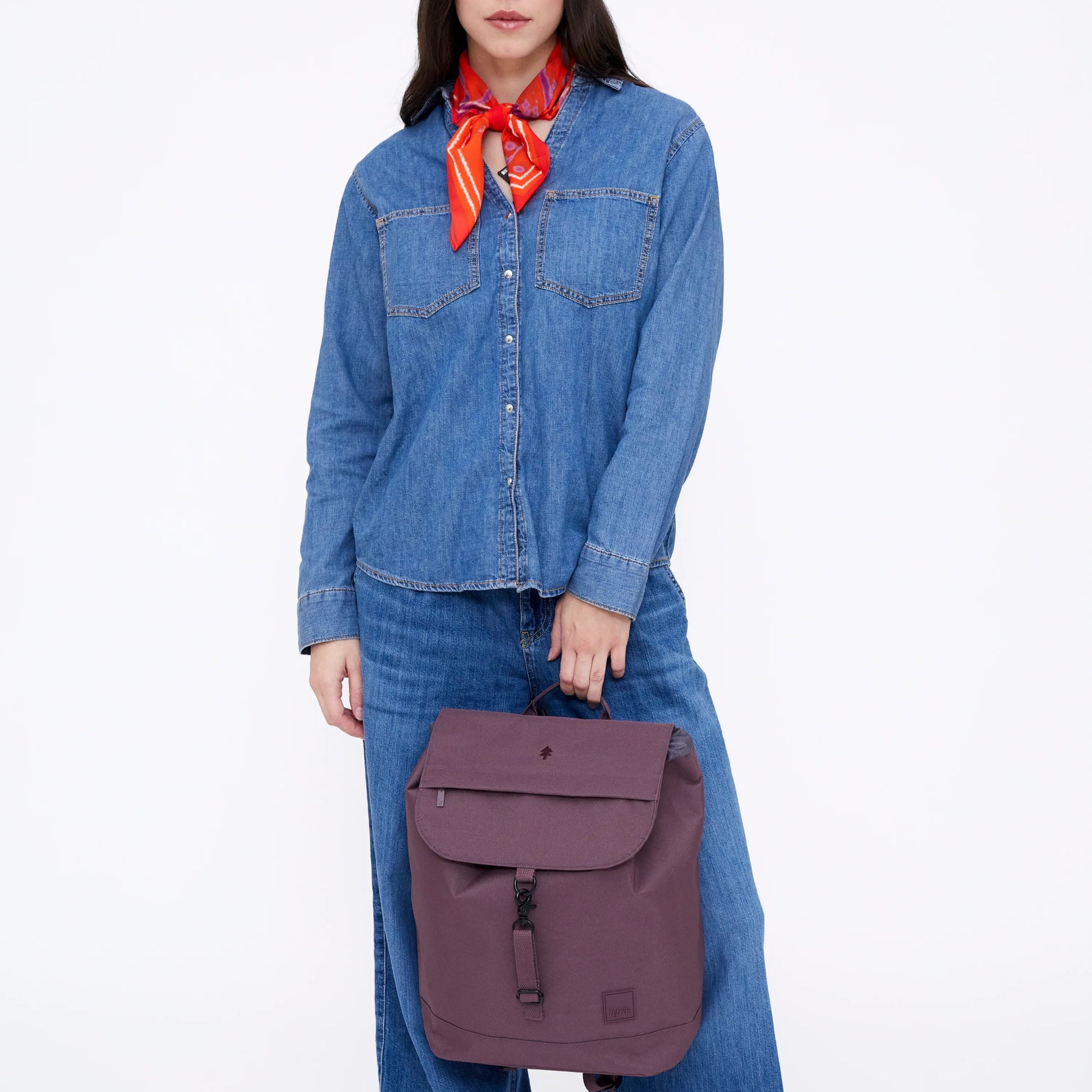 Mujer vestida de vaquero con la mochila Scout color morado berenjena de la marca española Lefrik en la mano