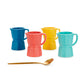 Juego de cuatro tazas de café expreso solo de cerámica de diferentes colores: azul, rosa, amarillo y turquesa junto a una cucharilla de café dorada