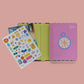Agenda Mi Superplán 2027 Rainbow Dancer Happimess abierta con plancha de stickers incluida y tapa rosa con brújula