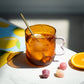 Taza de cristal ámbar con té con limón y hielo junto a unas gominolas y una rodaja de naranja