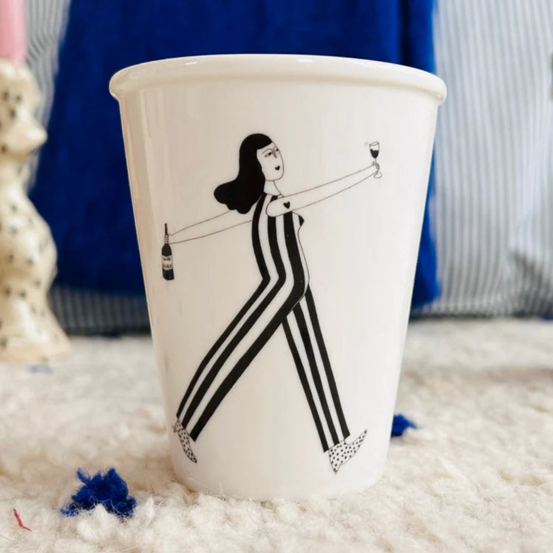 Taza blanca con el dibujo de una mujer feliz en negro sujetando una copa y una botella de vino. 
