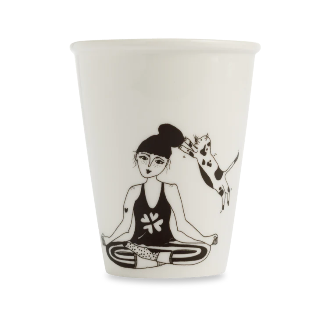 Taza en blanco y negro de una mujer intentando meditar ientras un gato le toca la cabeza. 