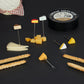 Seis tenedores de aperitivo Cheese Selection sobre fondo negro junto a la lata, palitos de pan con sésamo y distintas variedades de queso