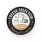 Vista cenital de la tapa de la lata redonda negra Cheese Selection con ilustración de quesos y jarra de leche, texto artisanal and organic y 6 premium forks