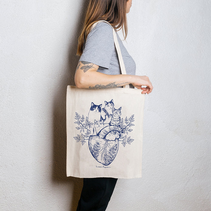 Mujer de perfil con una tote bag de algodón con ilustración de cuatro gatos sobre un corazón anatómico