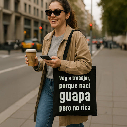 Mujer sonriente que camina en la calle con una ToteBAg en la que pone "voy a trabajar, porque nací guapa pero no rica"