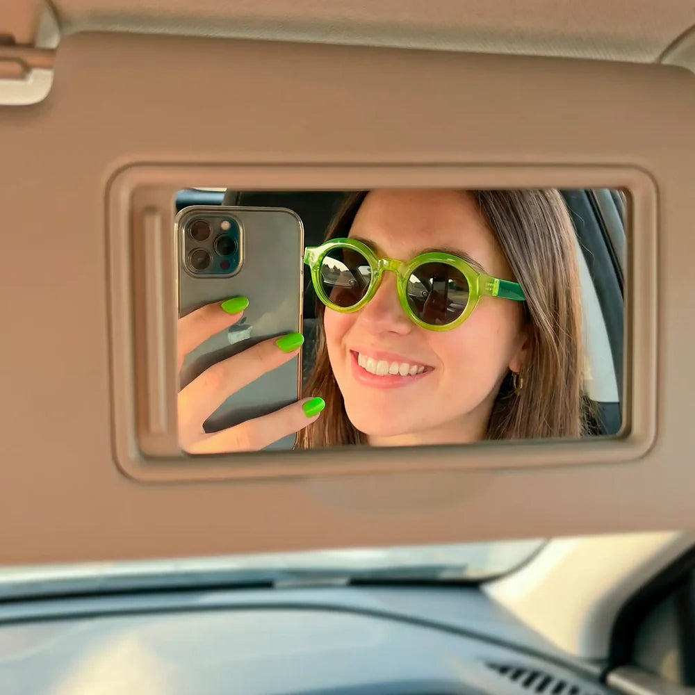 modelo posando con las gafas de sol de Fisura del modelo I'm not a tourist redondas con la parte delantera en color verde lima y los cristales en negro y las patillas en verde oscuro haciéndose una foto en el espejo del coche