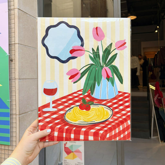 Ilustración de Laura Ortiz con una mesa con un mantel a cuadros y un plato de pasa, una copa de vino tinto y un florero con tulipanes