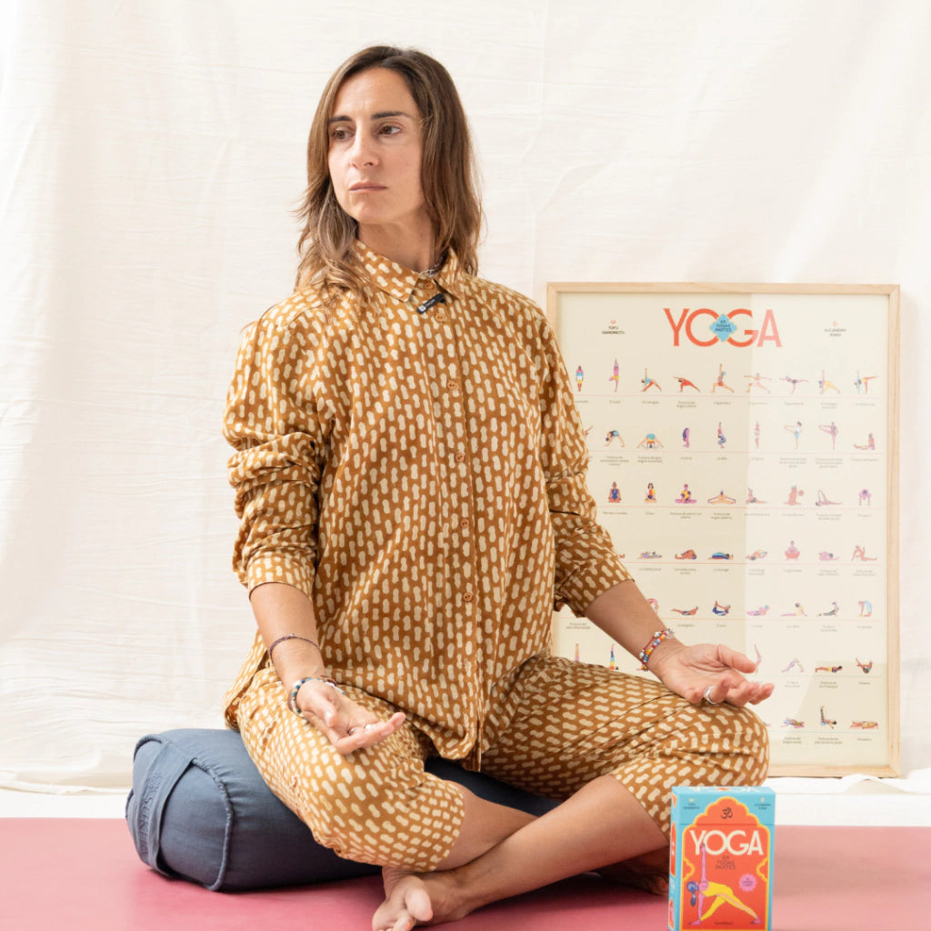 Tofu sentada en postura de loto con la guía con cartas ilustradas de diferentes posturas de yoga y manual de uso