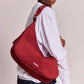 Modelo con camisa blanca llevando el bolso burdeos Bianca de Hindbag en el hombro, vista lateral que muestra la caída del asa y los herrajes ajustables.