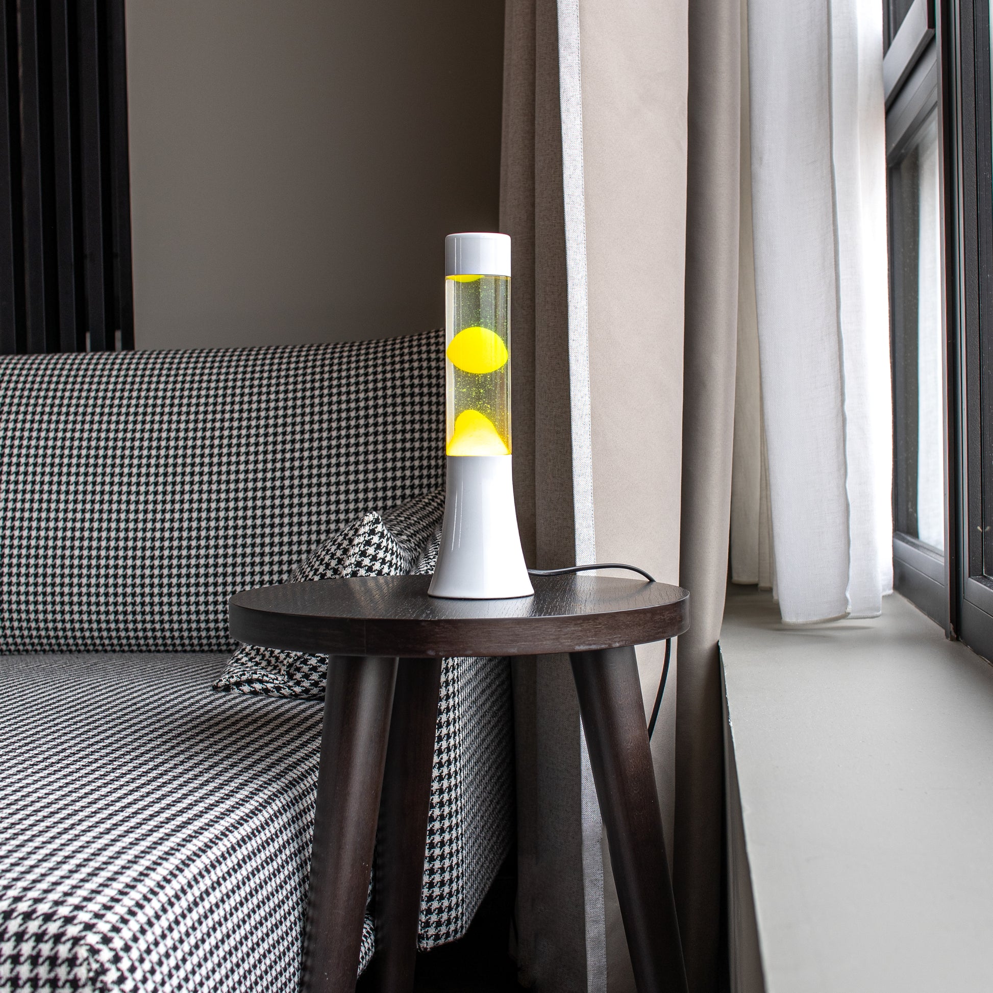 Lámpara de lava blanca con fluido amarillo sobre una mesa al lado de un sofa