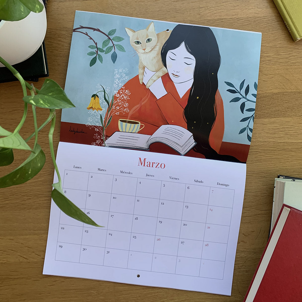 Marzo del calendario 2027 Leyendo, con una mujer junto a un libro abierto y un gato sobre su hombro.
