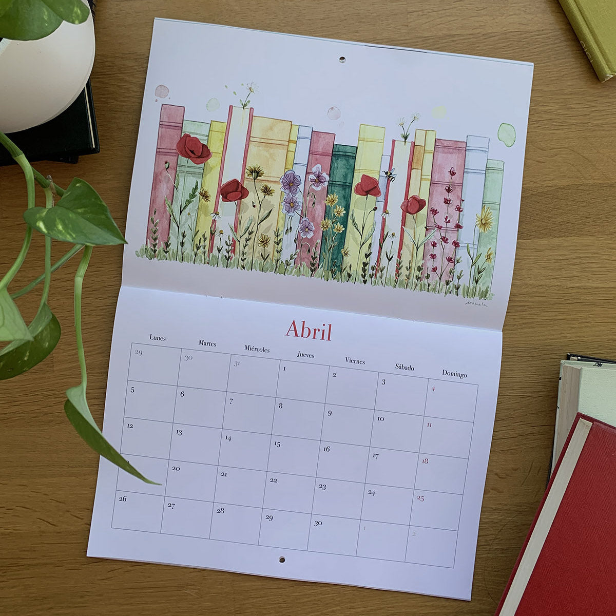 Abril del calendario 2027 Leyendo, con una fila de libros de colores entre flores silvestres.
