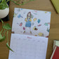 Calendario 2027 Leyendo abierto en mayo, con una niña rodeada de libros flotantes.