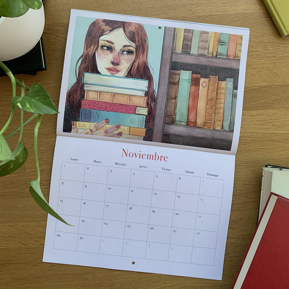 Noviembre del calendario 2027 Leyendo, con una joven sosteniendo una pila de libros junto a una estantería.

