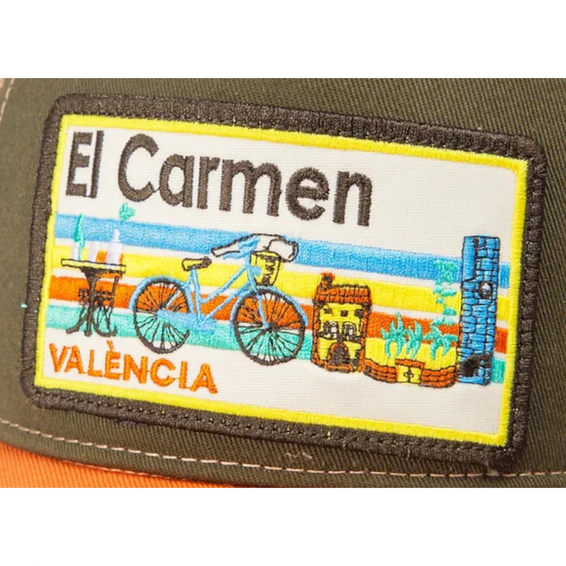 Detalle de gorra de Blocals con letras El Carmen València y objetos como bicicleta o mesa.