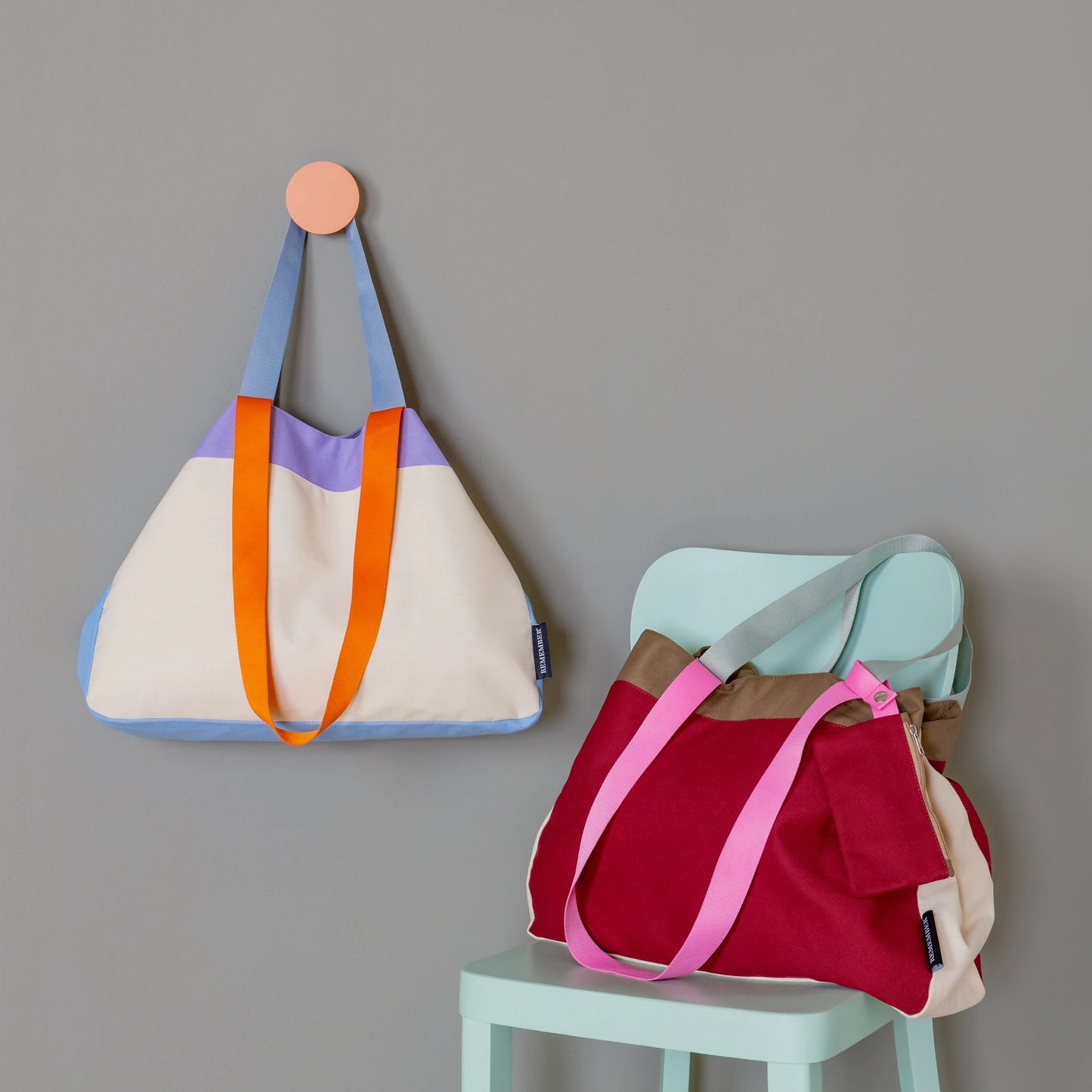 bolsas emma en color granate y toni en color beige con un toque azul, naranja y monrado de la marca alemana Remember sobre un fondo gris