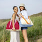 dos modelos llevando la bolsa emma en color granate y toni en color beige con un toque azul, naranja y monrado de la marca alemana Remember, posando en la playa