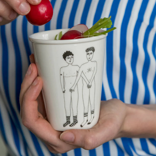 taza de porcelana con el dibujo en negro de dos chicos desnudos y con las manos tapando los genitales del otro